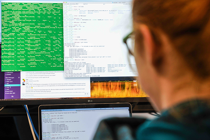 A  woman is looking at a computer screen with code on it