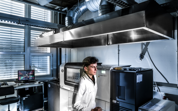 A young man in a lab with a laptop, evoking the clinical bioinformatics and personalized health