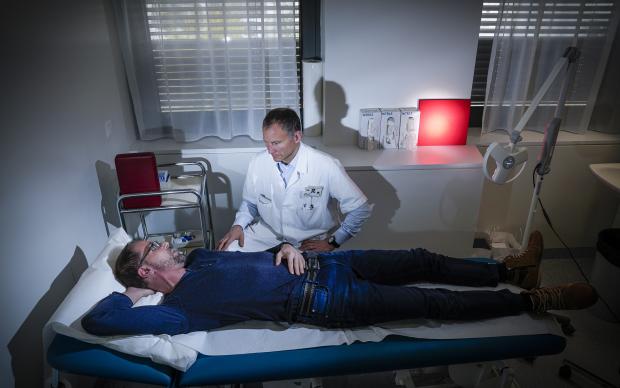 A man laying on a hospital bed with a doctor