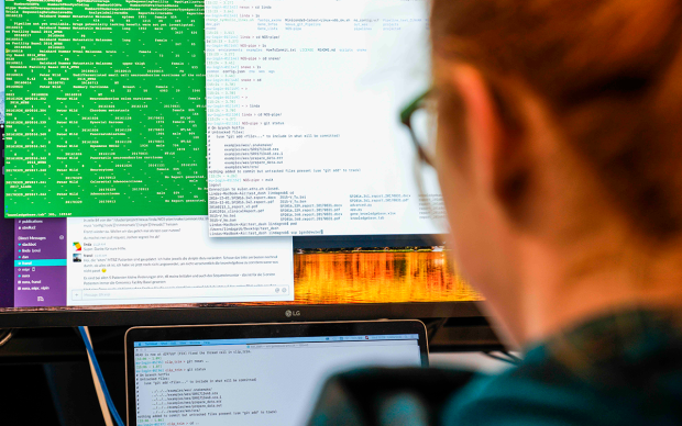 A  men is looking at a computer screen with code on it