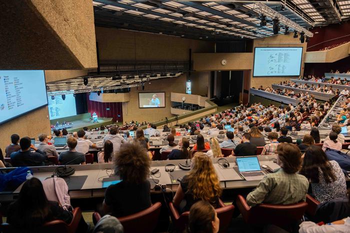 A crowded plenary room from a conference