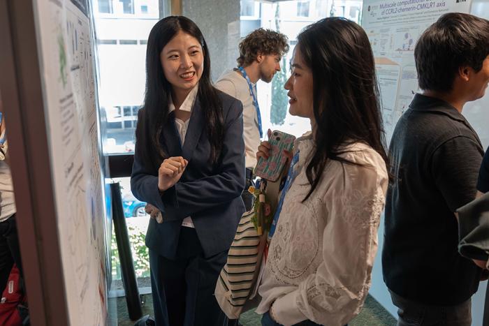 Two women talking in front of a scientific poster at a conference