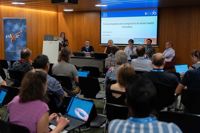 A crowded room from a scientific conference with people presenting