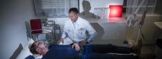 A man laying on a hospital bed with a doctor