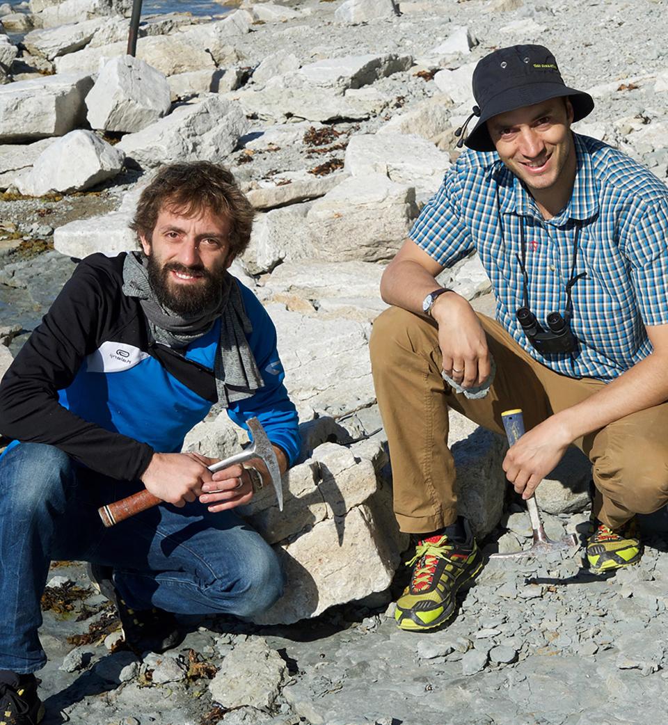 Two biologists in the field making measurements, equipped with a hammer for soil sampling